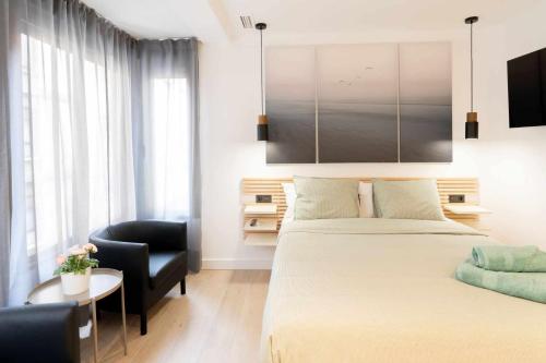 a bedroom with a bed and a chair and a table at Apartamento Venecia Living Suites en Castellón in Castellón de la Plana