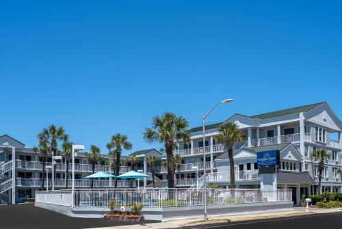 a large apartment building with palm trees and a street at The Sandbar Hotel, Trademark Collection by Wyndham in Myrtle Beach