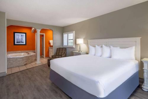 a bedroom with a large bed and a bath tub at The Sandbar Hotel, Trademark Collection by Wyndham in Myrtle Beach