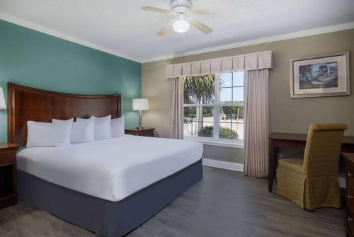 a bedroom with a bed and a desk and a window at The Sandbar Hotel, Trademark Collection by Wyndham in Myrtle Beach