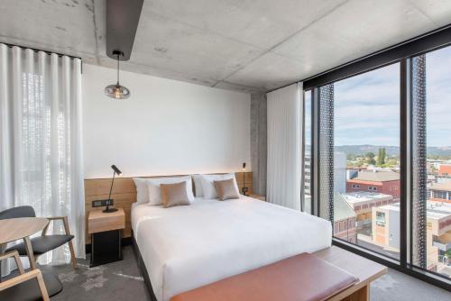 a bedroom with a white bed and a large window at Vibe Hotel Adelaide in Adelaide