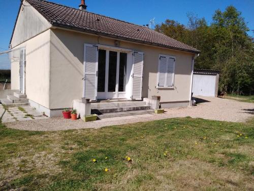 une petite maison blanche avec des volets bleus et une cour dans l'établissement Nuits paisibles à la campagne, à Vicq-sur-Nahon