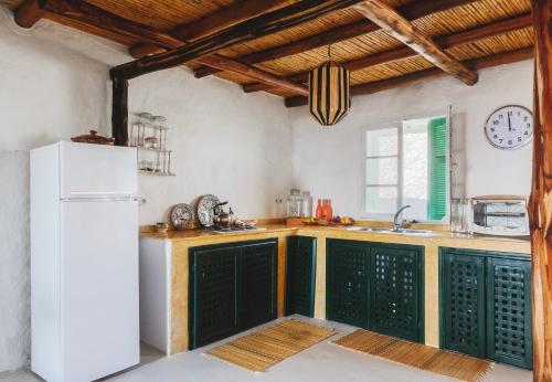 La cuisine est équipée de placards verts et d'un réfrigérateur blanc. dans l'établissement Khanfous Retreat, à Assilah