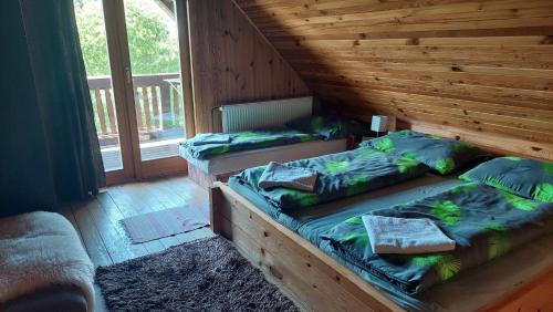 two twin beds in a wooden room with a window at Koliba Drabsko in Lom nad Rimavicou