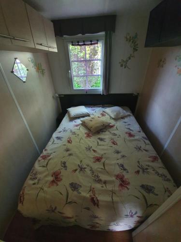 - une petite chambre dotée d'un lit avec un couvre-lit floral dans l'établissement Mobil Home, à Sainte-Eulalie-en-Born
