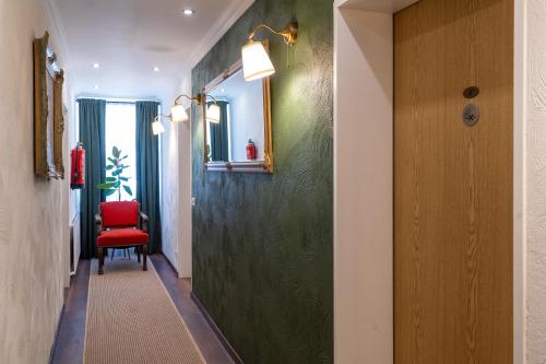a hallway with a green wall and a red chair at Jupa's Hotel in Düsseldorf