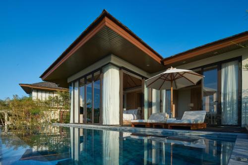 a house with a swimming pool and an umbrella at Cape Fahn Hotel - Private Islands Samui in Choeng Mon Beach