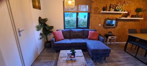 a living room with a blue couch and a table at Gezellige chalet met grote privétuin. in Dronrijp