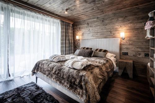sypialnia z dużym łóżkiem i drewnianą ścianą w obiekcie Luxury Chalet Na Stromym Wzgórzu & Sauna w Szczyrku