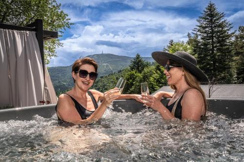 zwei Personen in einem Whirlpool mit einem Glas Wein in der Unterkunft Luxury Chalet Na Stromym Wzgórzu z sauną i balią in Szczyrk