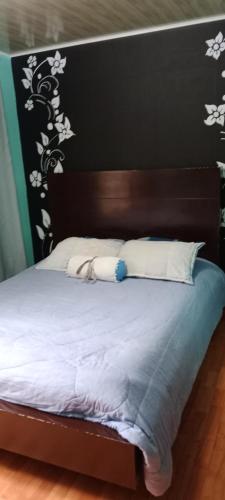 uma cama com cabeceira em preto e branco e almofadas brancas em Dulce sueños baño compartido em Chía