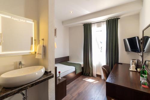 Jupa's Hotel في دوسلدورف: حمام مع مغسلة وسرير في الغرفة