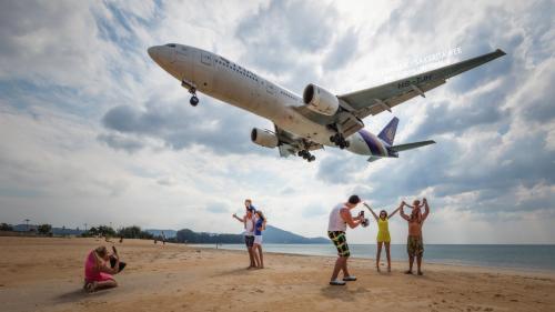 a group of people on a beach with an airplane at Dwell Phuket Airport Hotel at Naiyang in Nai Yang Beach
