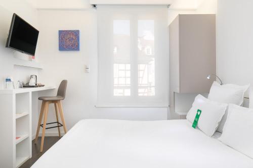 a white bedroom with a white bed and a desk at Hôtel de l'Europe by HappyCulture in Strasbourg