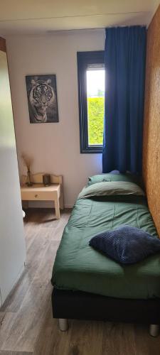 una camera da letto con un letto con una tenda blu e una finestra di Gezellige chalet met grote privétuin. a Dronrijp