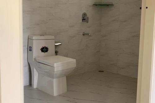 aseo blanco en un baño con paredes de mármol en Inno Farms, en Kharar