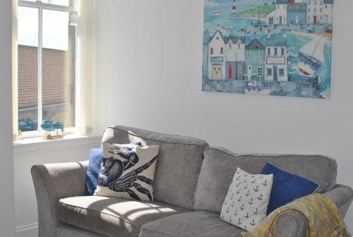 a living room with a gray couch with pillows at Bass View- harbourfront home Pittenweem in Pittenweem
