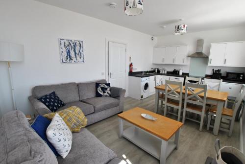 a living room with a couch and a table and a kitchen at Bass View- harbourfront home Pittenweem in Pittenweem