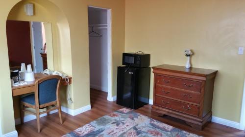 Zimmer mit einem Schreibtisch, einem Kühlschrank und einem Tisch in der Unterkunft Slumber Motel in Merced