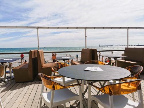 une terrasse avec des tables et des chaises et la plage dans l'établissement Le Petit Foch - Face a la plage, à Les Sables-dʼOlonne
