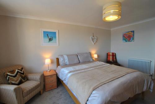 ein Schlafzimmer mit einem Bett, einem Stuhl und zwei Lampen in der Unterkunft Aqua Vista- seafront cottage Cellardyke in Anstruther