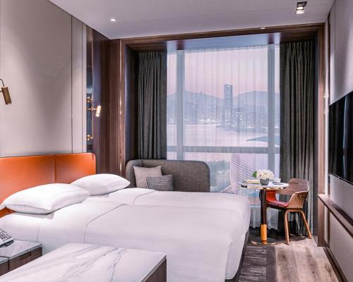 a hotel room with two beds and a window at Dorsett Kai Tak in Hong Kong
