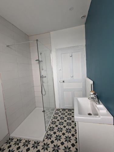 une salle de bain blanche avec une douche et un lavabo dans l'établissement Un rêve à la mer, à Plestin-les-Grèves