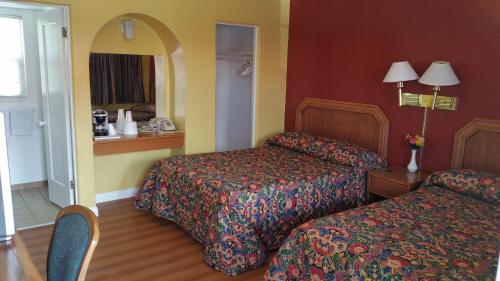 Habitación de hotel con 2 camas y espejo en Slumber Motel en Merced