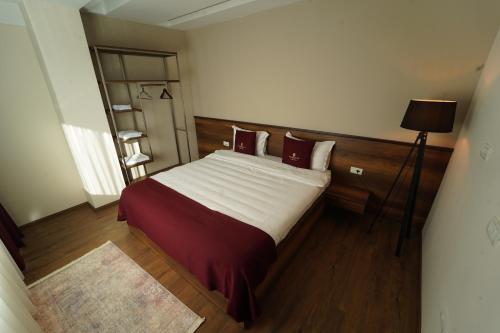 a bedroom with a large bed with red pillows at Monarch Hotel in Prizren