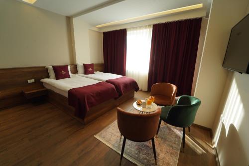 a hotel room with a bed and a table and chairs at Monarch Hotel in Prizren