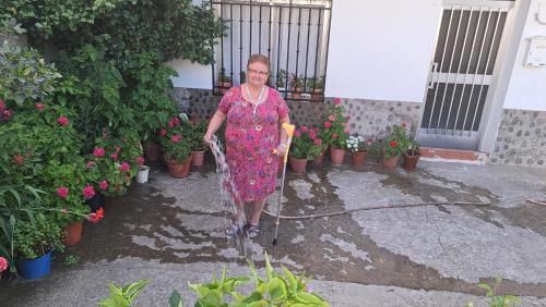 a woman in a dress with a garden hose at Casa Rural El Chorritero in Ovejuela