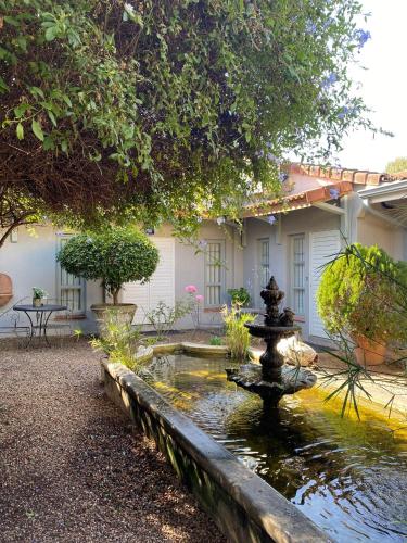 a fountain in the middle of a garden with a building at Maison H Guest House in Durban
