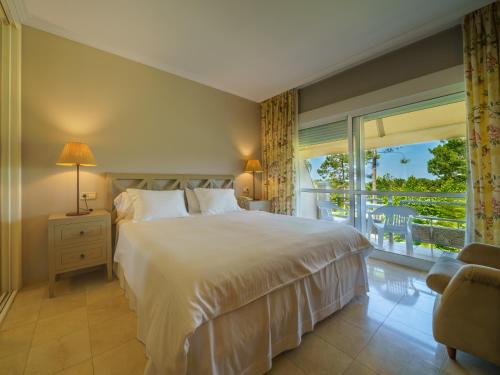 a bedroom with a large bed and a balcony at Hotel Spa Atlántico San Vicente do Mar in San Vicente do Mar