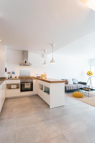 a kitchen with white cabinets and a living room at SUNSET1 - By Smarthomes in São Martinho do Porto