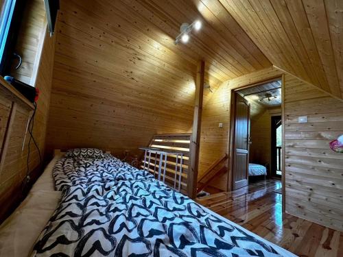 un grande letto in una camera con parete in legno di Domek letniskowy Aster z basenem i jacuzzi a Maldyty