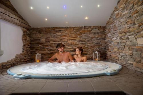 Ein Mann und eine Frau sitzen in einer Badewanne in der Unterkunft Hotel Ramon in Campitello di Fassa