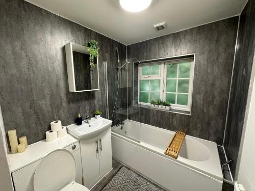 a bathroom with a sink and a toilet and a bath tub at Comfortable 3 Bed House with Garden & Parking in Nottingham