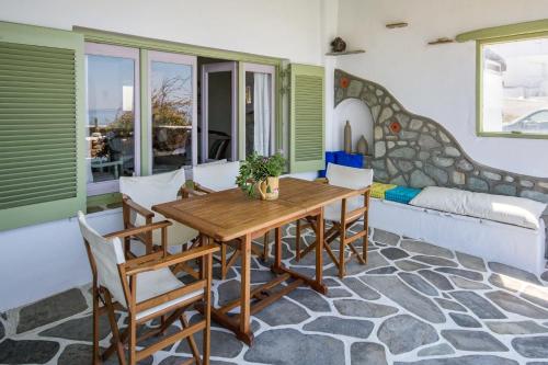 Tourlos Beachfront House in Mykonos في تورلوس: غرفة طعام مع طاولة وكراسي خشبية
