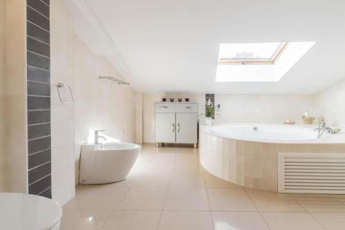 Baño blanco con bañera y lavamanos en Sand Bay Beach Duplex, en Girona