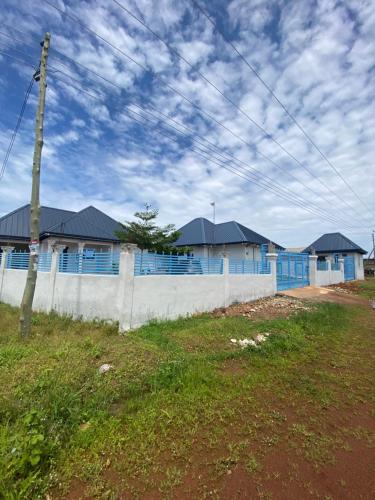 una casa con ventanas azules y una valla blanca en Buzu Apartments, en Tamale