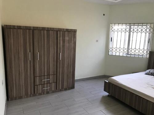 a bedroom with a large wooden cabinet next to a bed at Buzu Apartments in Tamale