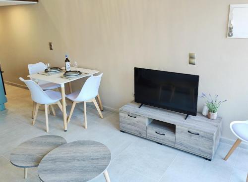 a living room with a table and a television on a wooden cabinet at Avramiou Loft Studio in Agios Rokkos