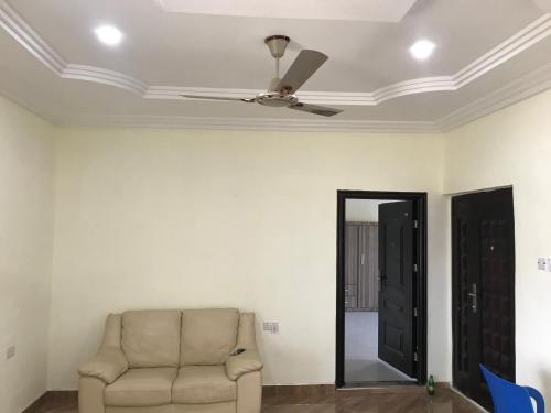 - un salon avec une chaise et un ventilateur de plafond dans l'établissement Buzu Apartments, à Tamale