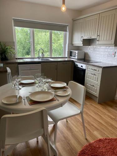 a kitchen with a white table and chairs and a kitchen with a sink at Leaba On The Lake in Killaloe