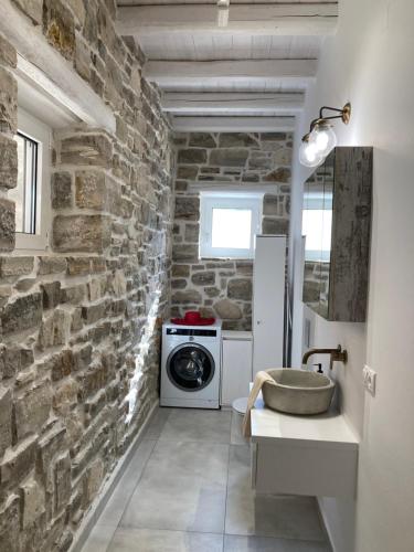 een badkamer met stenen muren, een wastafel en een wasmachine bij VILLA LEVANTA - Das ideale Wohlfühl-Refugium Aussicht, Komfort, Erholen, Home Office in Pitsidia
