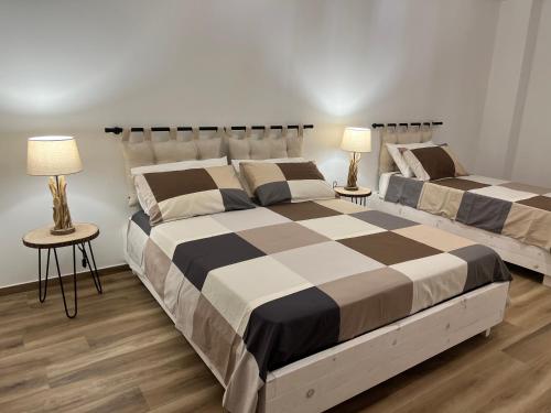 two beds in a bedroom with two tables and two lamps at Al Vicolo Stretto in Brancaleone Marina