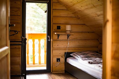 a bed in a wooden room with a window at Na Wzgórzu Domki z Bali -Jacuzzi, Balia, Spa in Polańczyk