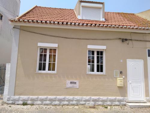 a small house with a white door and two windows at Casa Guti in Costa da Caparica