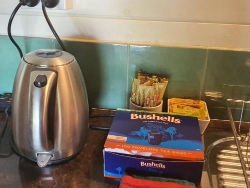 a kitchen counter with a tea kettle and a box of biscuits at The Bushranger Hideaway in Midginbil