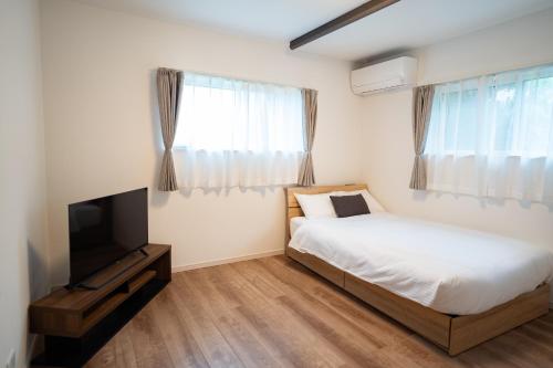 a bedroom with a bed and a flat screen tv at Comfy Resort Villa Onna in Onna